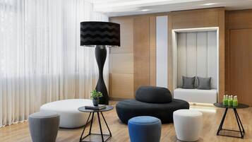 Un salon moderne avec un canapé, des poufs, une lampe et une petite table sur laquelle sont posées des bouteilles.