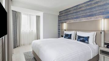 A modern hotel room with a large bed, a flat-screen TV, and a view of the outdoors.