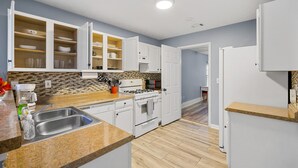 Een moderne keuken met witte kastjes, een granieten aanrechtblad, een roestvrijstalen spoelbak en een inbouwoven.