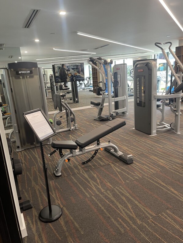 A gym with various exercise equipment, including a bench, weight machines, and cardio machines. - NEW Luxury Apartment!! (West Miami)