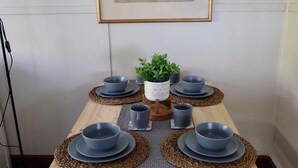Una mesa de comedor dispuesta con seis cuencos y platos grises, una planta en maceta y un camino de mesa estampado.