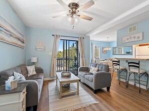 Un salon spacieux doté d’un ventilateur de plafond, de deux canapés, d’une table basse et d’un coin repas avec des chaises.