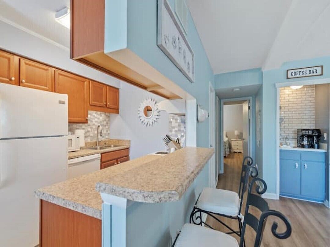 A kitchen with wooden cabinets, a granite countertop, and a coffee bar area.
