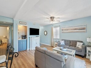 A living room with a sofa, coffee bar, and a television.