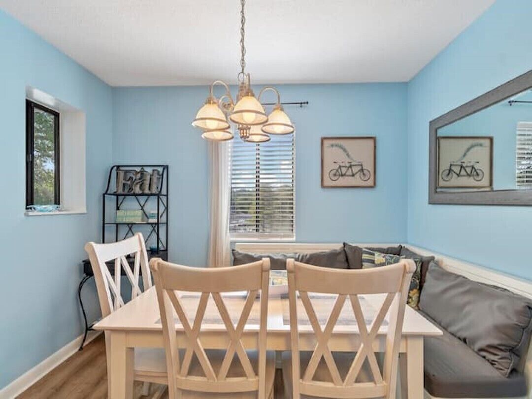 Un comedor con una mesa y sillas, una ventana con persianas y una obra de arte de bicicleta colgada en la pared.
