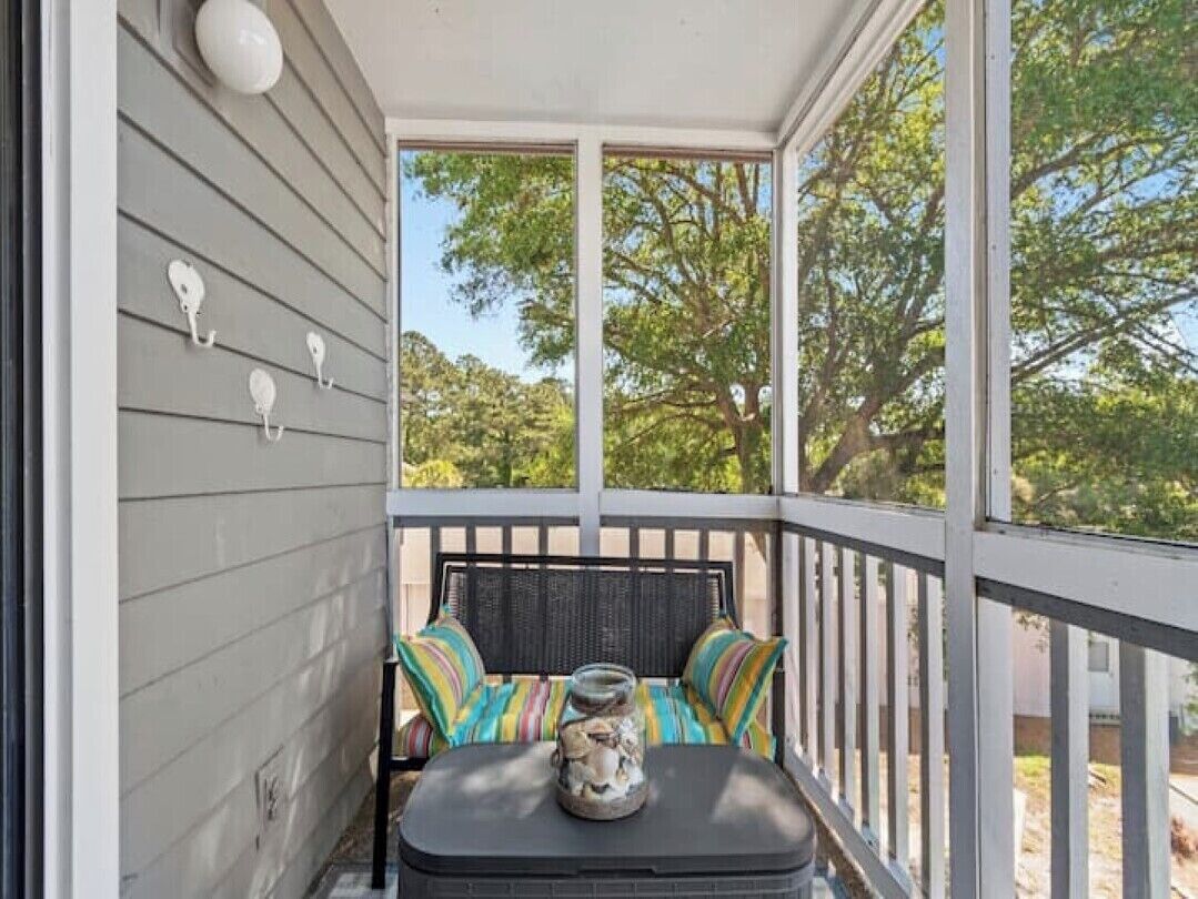 A covered porch with a table and chairs, a decorative jar, and wall-mounted hooks.