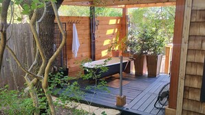 A wooden deck with a built-in shower, surrounded by potted plants and a wooden fence.