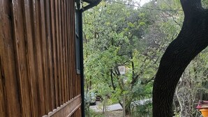 A wooden pathway leading to a building with a window, surrounded by pebbles and a tree.