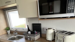 Une cuisine compacte équipée d’un four à micro-ondes, d’un grille-pain, d’un évier et d’un lave-vaisselle.