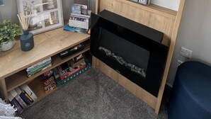 Une pièce chaleureuse avec une bibliothèque en bois, un tableau encadré et une fenêtre avec des rideaux.