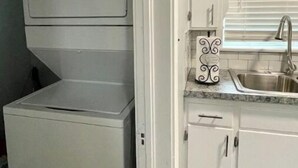 Een compacte keuken met een inbouw wasmachine en droger, een spoelbak en witte keukenkastjes.