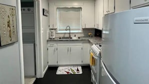 Een kleine keuken met witte kastjes, een roestvrijstalen spoelbak, een gasfornuis en een Frigidaire koelkast.