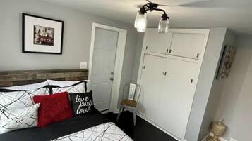 Een slaapkamer met een bed, een garderobe, een stoel en een plafondlamp.