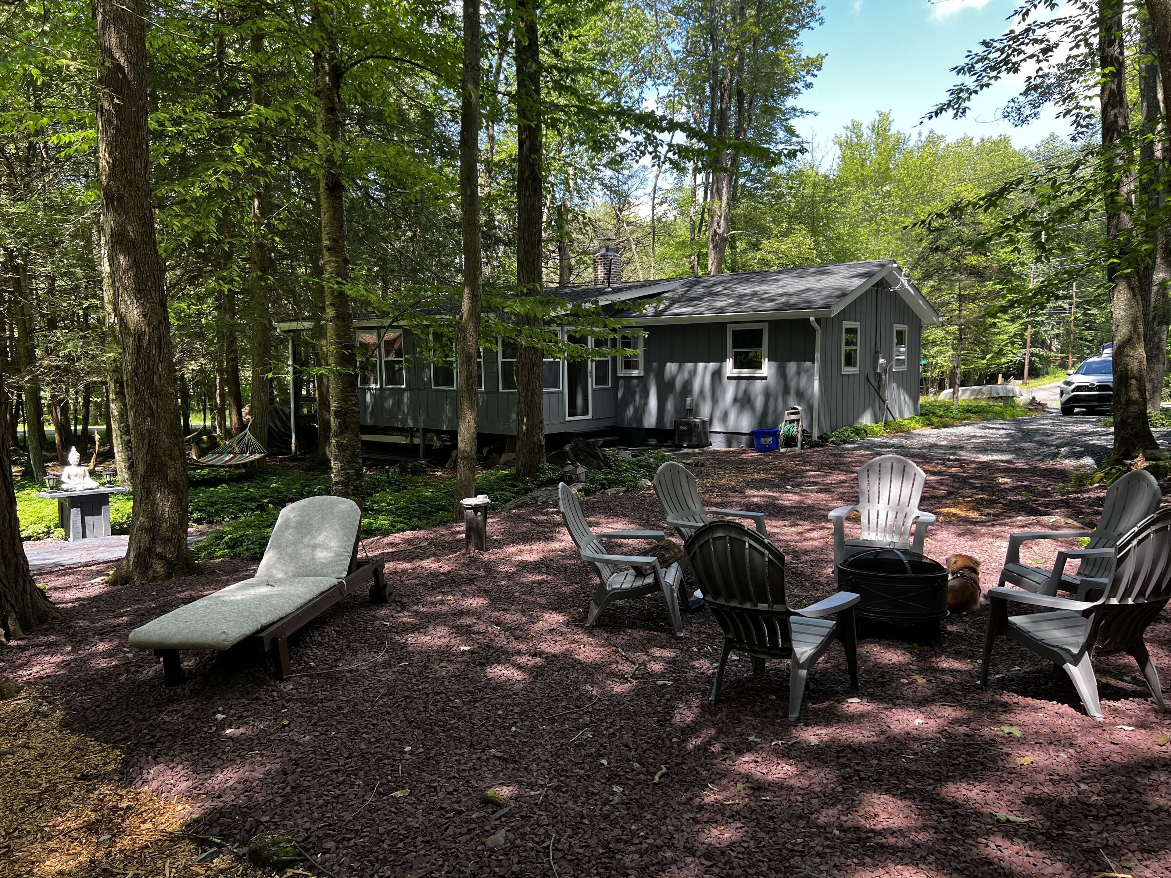 A cabin with a deck, surrounded by trees, and equipped with outdoor seating.