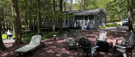 A cabin with a deck, surrounded by trees, and equipped with outdoor seating.