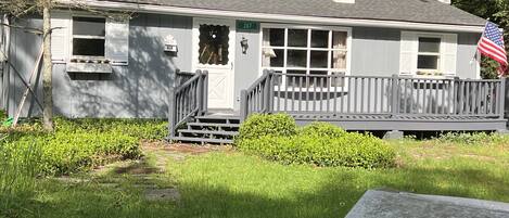 A single-story house with a front porch, a chimney, and an American flag.