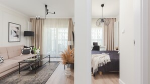 A modern living room with a sofa, coffee table, and a dining area with a table and chairs.