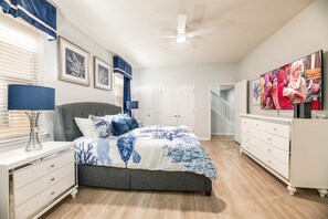 A bedroom with a bed, a dresser, a TV, and a ceiling fan.