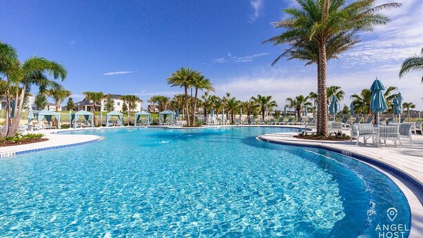 A large, clear swimming pool surrounded by palm trees and lounge chairs, with a clear blue sky above. - Two Villas Two Resorts Two Blocks Apart Sleeps 41 (Kissimmee)