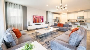A modern living room with grey sofas, a coffee table, and a painting on the wall. - Two Villas Two Resorts Two Blocks Apart Sleeps 41 (Kissimmee)
