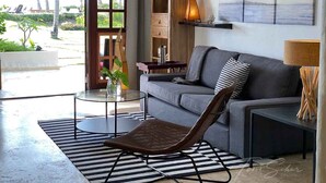 Een moderne woonkamer met een grijze bank, een houten dressoir, een glazen salontafel en een gestreept vloerkleed.
