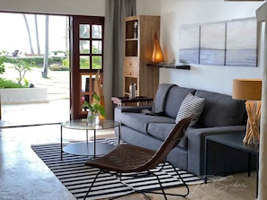 Uma sala de estar moderna com um sofá cinza, um aparador de madeira, uma mesa de centro de vidro e um tapete listrado.