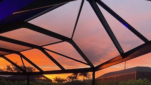 Une piscine extérieure dotée d’une structure de toit aux lignes géométriques et offrant une vue sur le coucher de soleil.