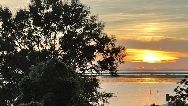 Two Adirondack chairs facing a body of water with a sunset in the background. - DAPHNE SCENIC BAY VIEW CONDO (Daphne)