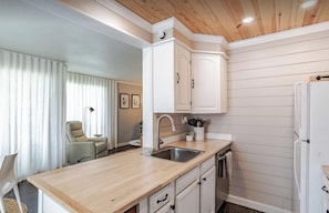 A modern kitchen with white cabinets, a stainless steel sink, and a wooden countertop.