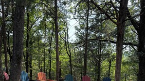 Metsäleirintäalue, jossa on Adirondack-tyylisiä puutarhatuoleja ja nuotiopaikka.