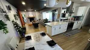 Una cucina moderna con mobili bianchi, un piano di lavoro in marmo e un'area pranzo con tavolo apparecchiato per quattro persone.