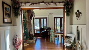 A spacious living room with a wooden floor, a chandelier, and a Christmas tree. - Luxury 7 bedroom mansion with horses, pool, hot tub, pond, swings and fire pit!  (Waverly)
