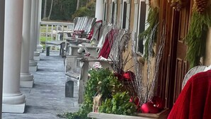 A covered porch with white columns, outdoor seating, and Christmas decorations. - Luxury 7 bedroom mansion with horses, pool, hot tub, pond, swings and fire pit!  (Waverly)