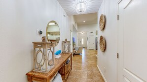 Un couloir avec un banc en bois, un miroir et des éléments décoratifs accrochés au mur.
