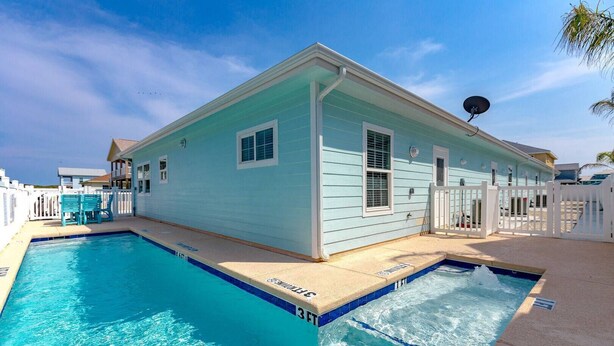 Un bâtiment bleu clair avec une piscine, une clôture blanche et une antenne parabolique.