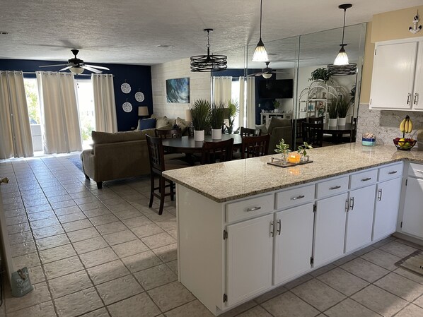 A modern kitchen with white cabinets, a granite countertop, and a dining area with a table and chairs.