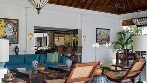 A spacious lobby with a blue sofa, wooden chairs, a coffee table, and decorative items like vases and sculptures. - Villa Windu Asri (Seminyak)