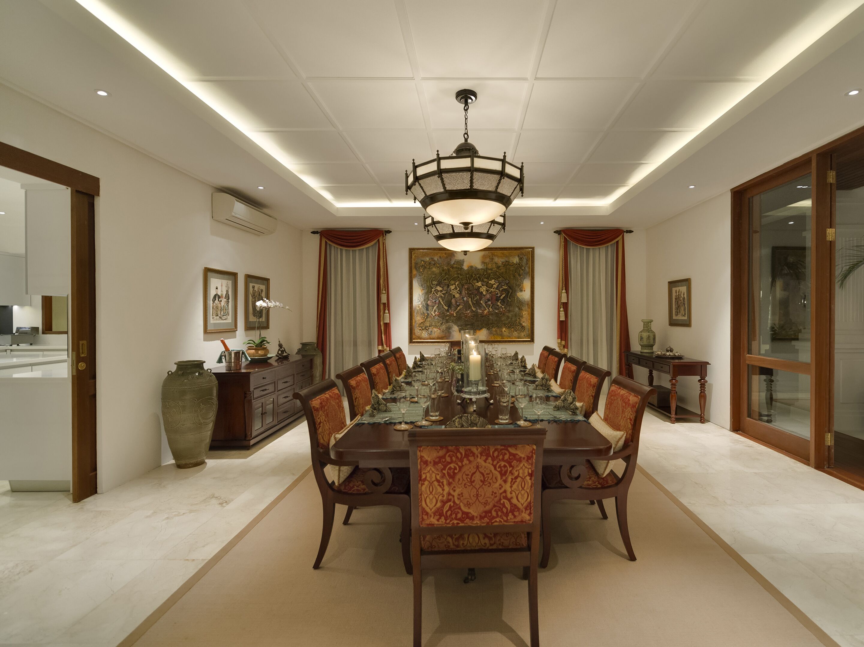 A formal dining room with a long table, chairs, a chandelier, and artwork on the walls.
