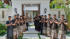 A group of people standing in front of a building with a white facade and a wooden entrance. - Villa Windu Asri (Seminyak)