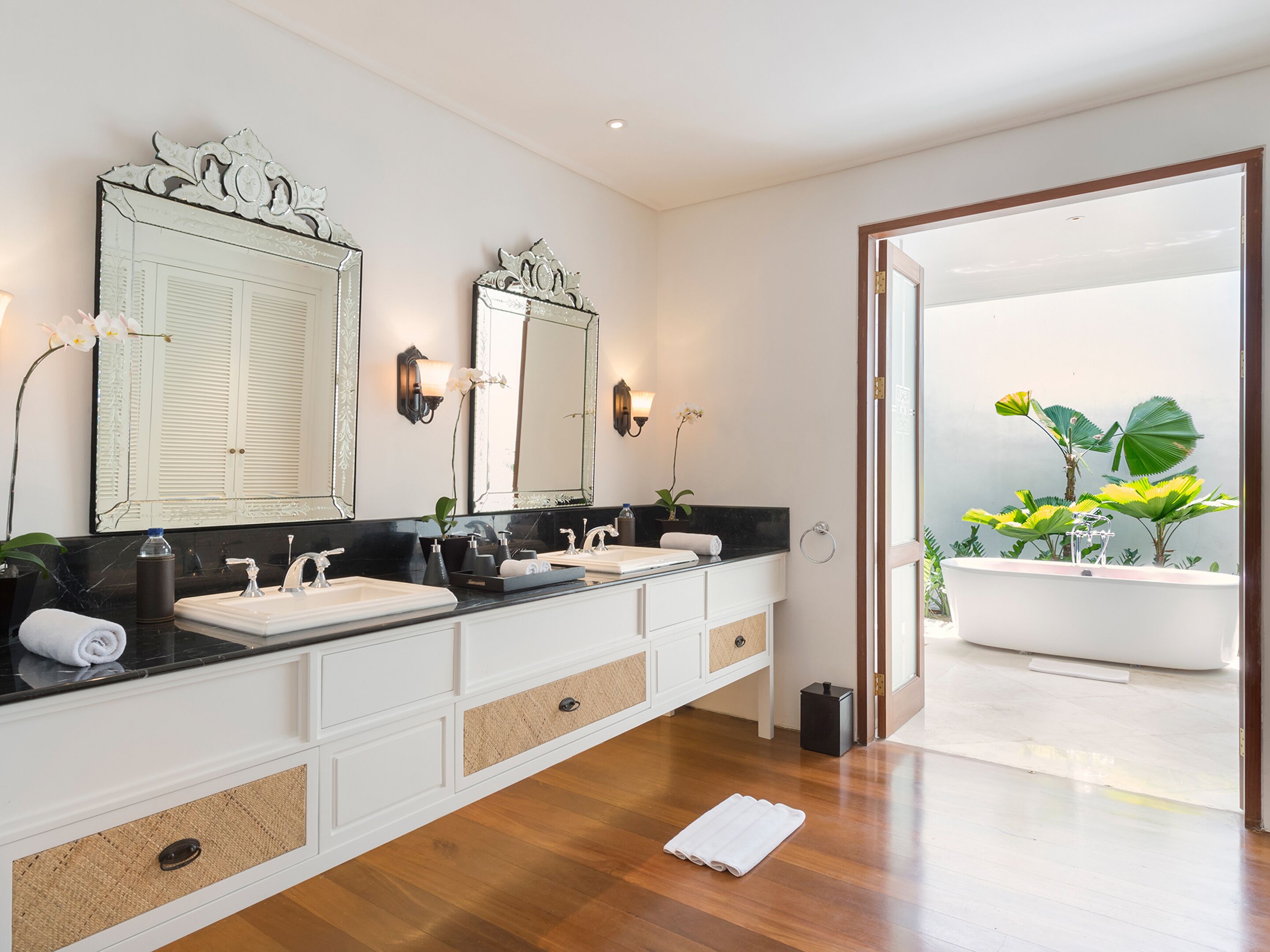 A modern bathroom with two sinks, a large mirror, and a bathtub.