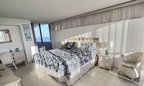 A bedroom with a large bed, a desk, a chair, and a nightstand.