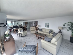 A spacious living area with a sofa set, a coffee table, and a dining table.