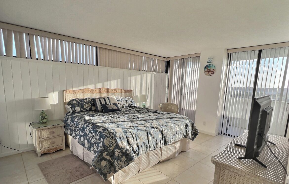 Une chambre à coucher avec un lit, une table de chevet, une lampe et un téléviseur posé sur un meuble.