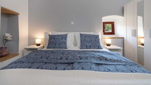 A bedroom with a bed, two bedside tables with lamps, a nightstand, a wooden shelf with a vase, and a wardrobe. - Holiday House Stone Lady (Rasopasno)