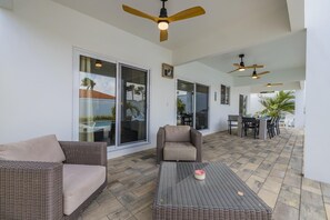 Un patio couvert aménagé avec des meubles en osier, des ventilateurs de plafond et une table à manger.