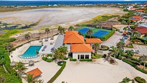 Vue aérienne d’un complexe hôtelier doté d’une piscine, de courts de tennis et d’une plage.