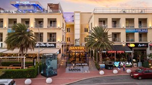 A commercial building with multiple businesses including a coffee shop named SANTOS, a restaurant called On The Rocks, and a Drunken Burger steakhouse. - NEW 2BR Condo in  of Palm Beach! Walk 2 Beach! (Palm Beach)