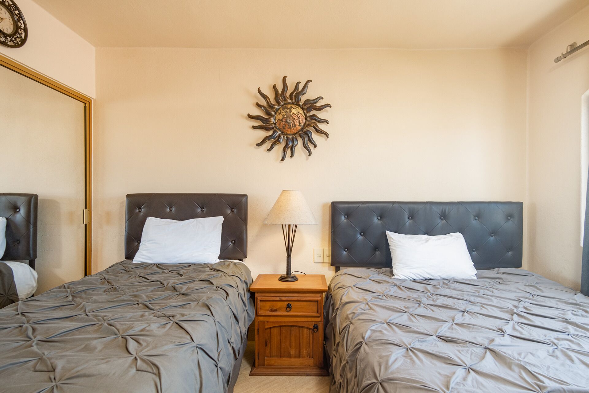 Een slaapkamer met twee bedden, een nachtkastje, een lamp en een decoratie aan de muur.