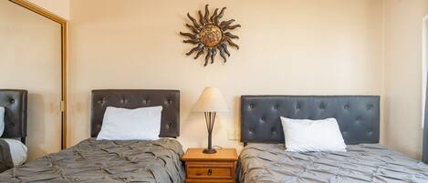 Een slaapkamer met twee bedden, een nachtkastje, een lamp en een decoratie aan de muur.
