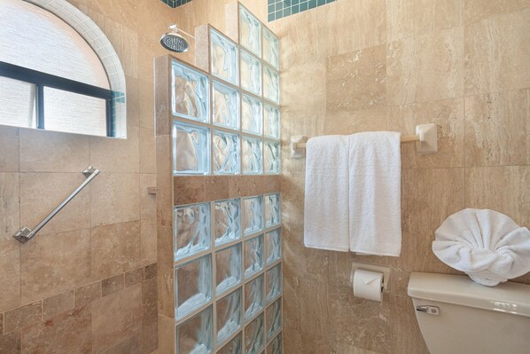 Un baño con cabina de ducha de vidrio, un perchero y un inodoro.